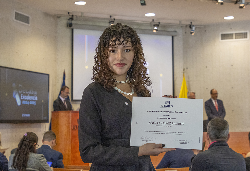 Una de las estudiantes reconocida con la Beca Excelencia posa con su diploma