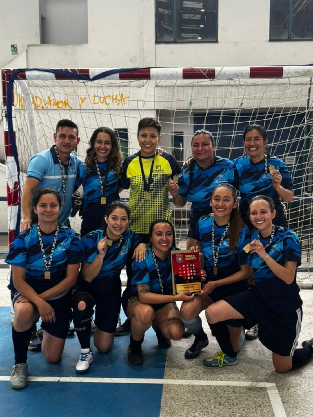 Jugadores del equipo femenino de fútbol de salón posando junto al trofeo